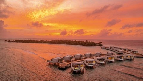Overwater-Villen des Alila Kothaifaru Maldives bei leuchtendem Sonnenuntergang über dem Indischen Ozean