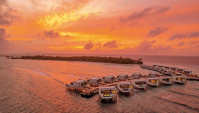 Overwater-Villen des Alila Kothaifaru Maldives bei leuchtendem Sonnenuntergang über dem Indischen Ozean