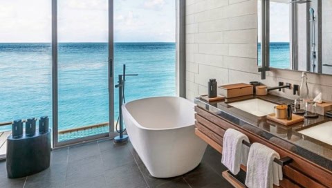 Modernes Badezimmer der Sunset Overwater Pool Villa mit freistehender Badewanne und Meerblick
