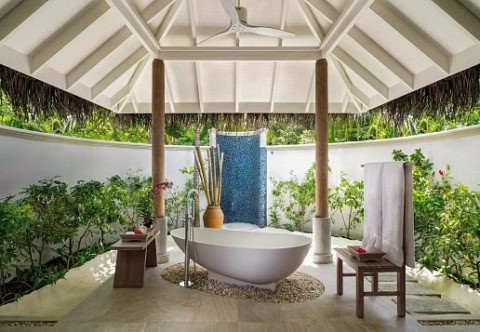 Freistehende Badewanne im offenen Gartenbad einer Villa.