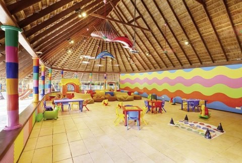 Kinderclub mit buntem Spielbereich unter Strohdach.