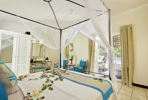 Schlafzimmer mit Himmelbett und tropischer Dekoration.