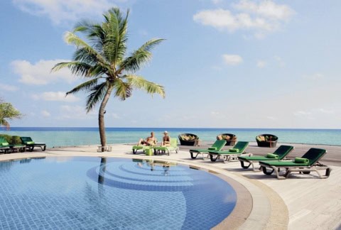 Poolbereich mit Sonnenliegen direkt am Meer.