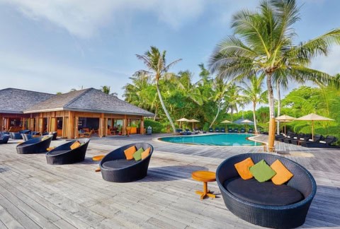 Poolterrasse mit Lounge-Möbeln und Palmen im Kuredu Island Resort auf den Malediven