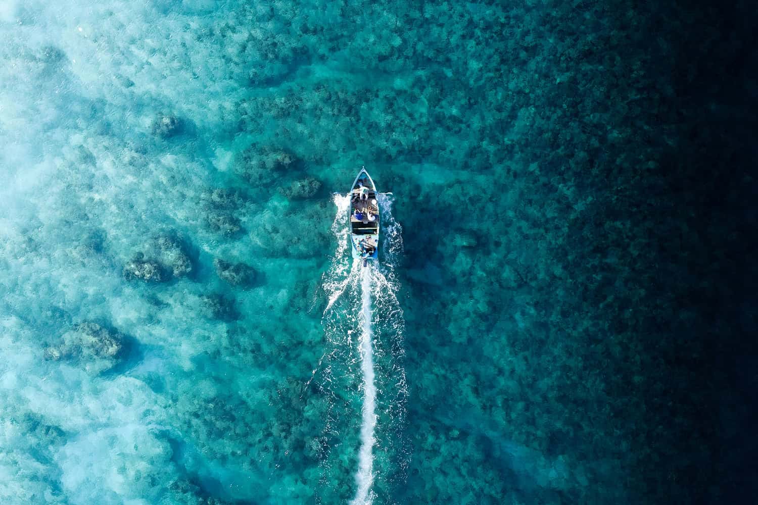 Boot aus der Luft über türkisfarbenem Wasser und Korallenriffen der Malediven mit sichtbaren Sandbänken
