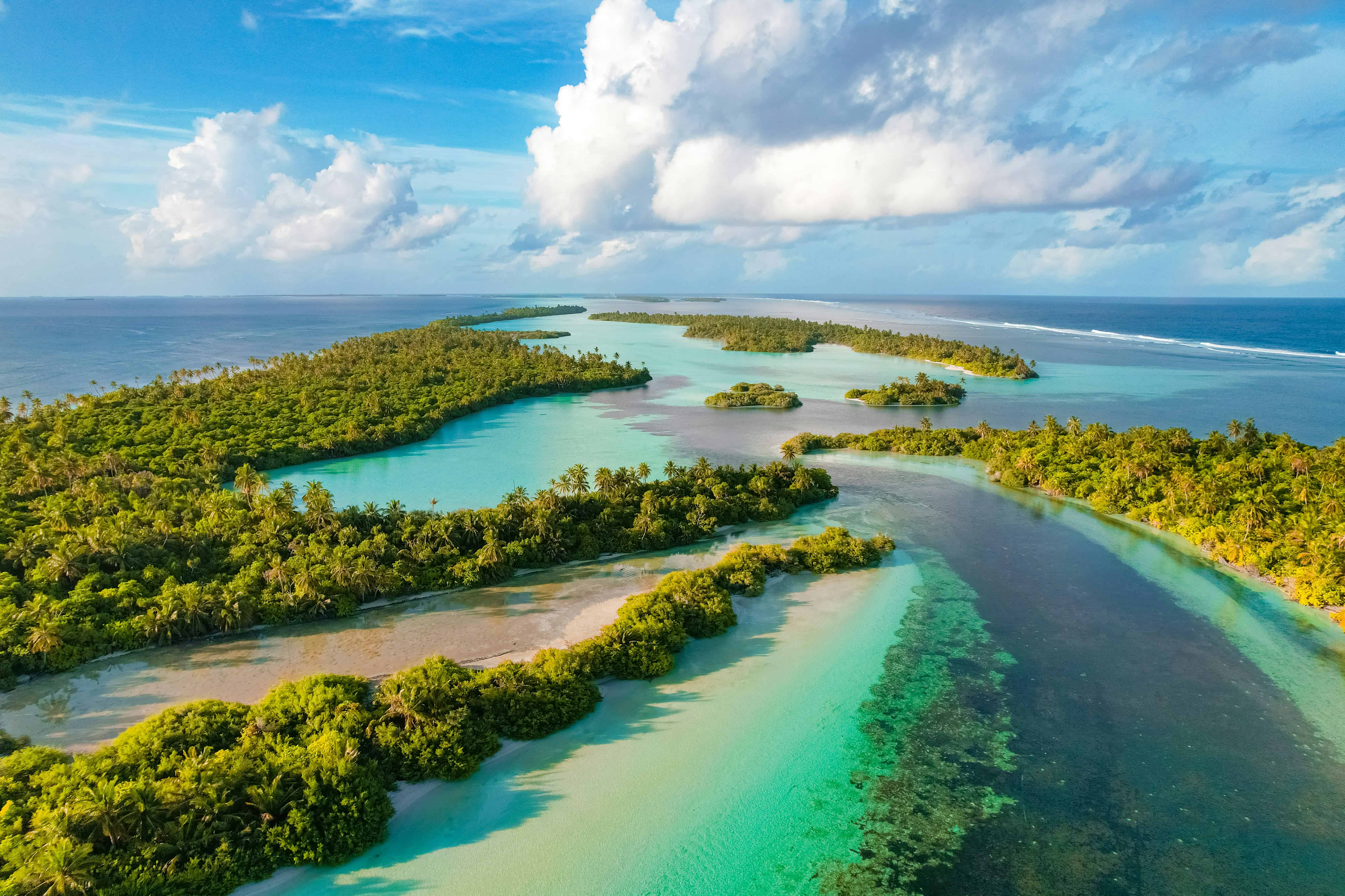 Luftaufnahme eines tropischen Atolls mit türkisfarbenen Lagunen und grünen Inseln im Indischen Ozean