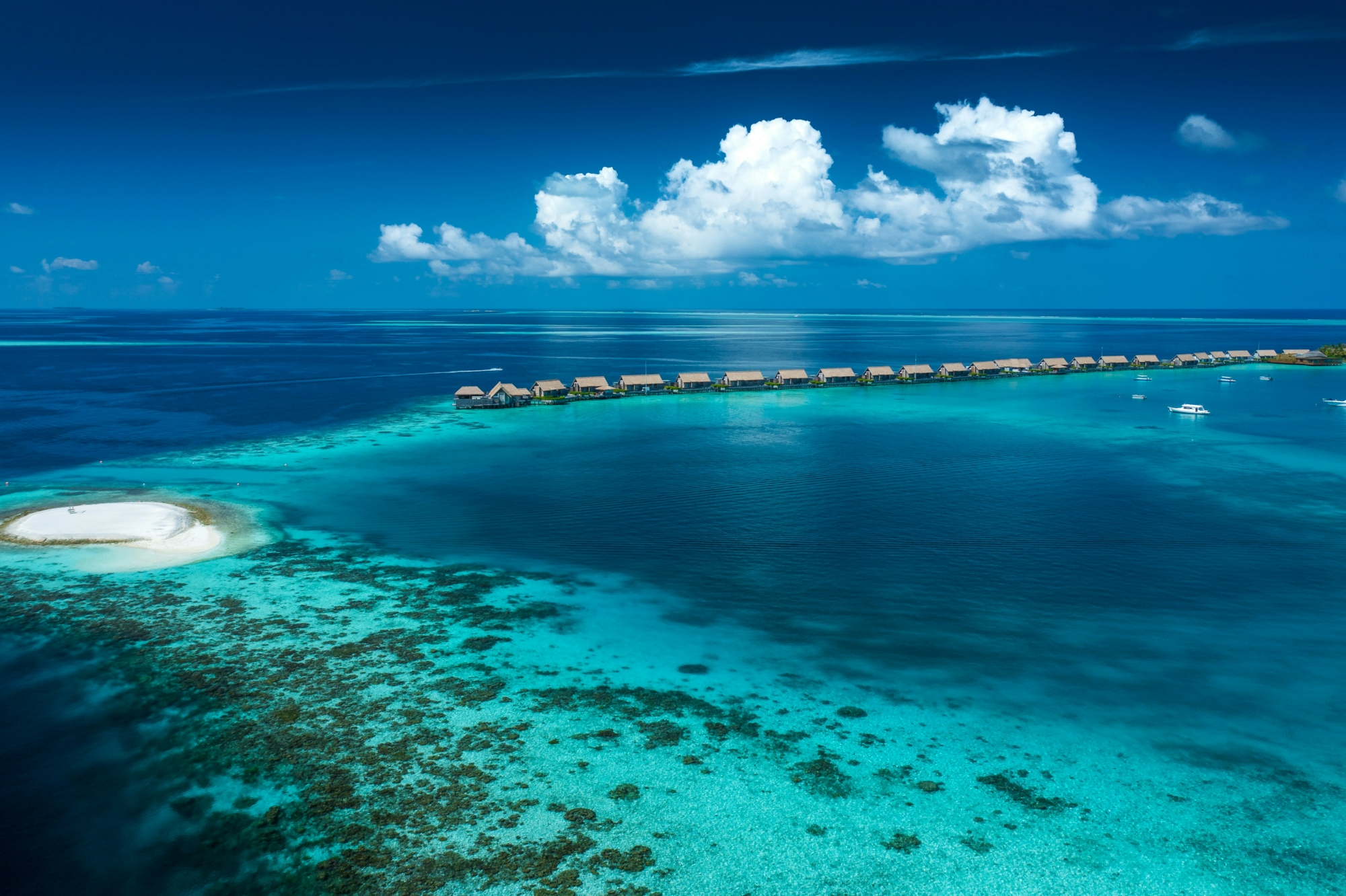 Weite Lagune auf den Malediven mit türkisfarbenem Wasser und einer Reihe von Wasserbungalows am Horizont