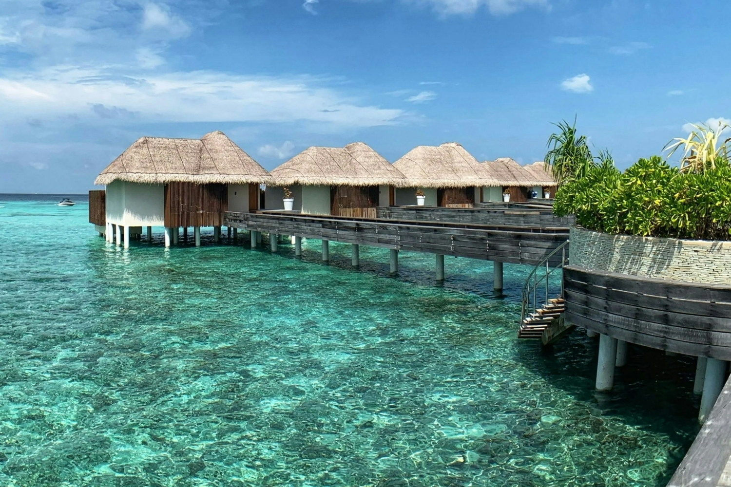 Helle Wasserbungalows stehen auf Stelzen über kristallklarem Wasser und sind über einen Holzsteg verbunden