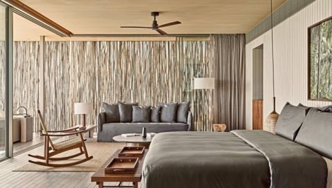 Schlafbereich der One Bedroom Beach Pool Villa mit großem Bett, Sitzsofa und bodentiefen Fenstern