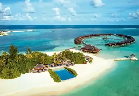 Wasserbungalows in geschwungener Anordnung über kristallklarem Meer.