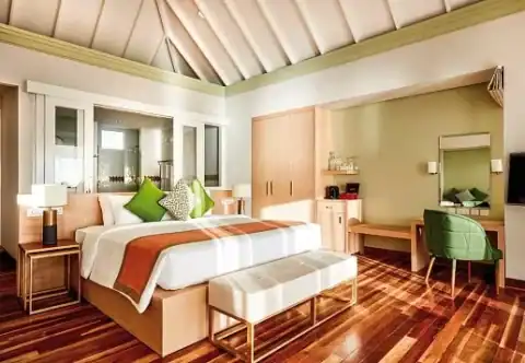 Modern eingerichtetes Schlafzimmer mit Holzboden im Sun Siyam Olhuveli.