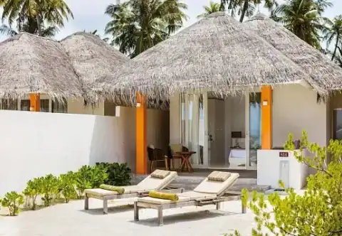 Strandvilla mit Strohdach, privater Terrasse und Liegen im Sun Siyam Olhuveli auf den Malediven.