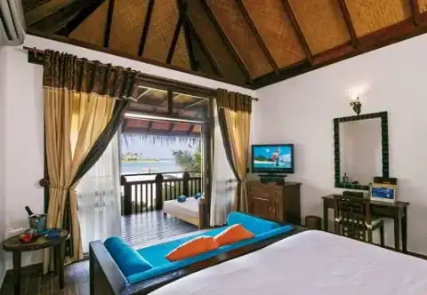Schlafzimmer einer Wasser-Villa im Sun Siyam Olhuveli mit Meerblick und direktem Zugang zur Terrasse.