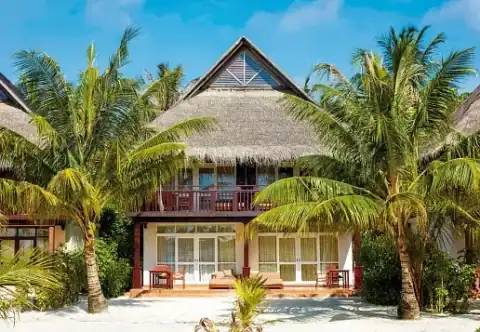 Strandvilla mit Strohdach und Palmen im Sun Siyam Olhuveli Resort auf den Malediven.