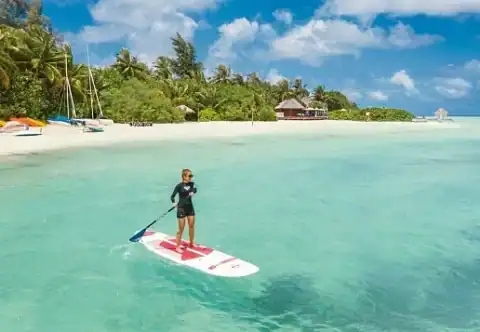 Gast beim Stand-up-Paddling in der türkisfarbenen Lagune vor dem Resort.