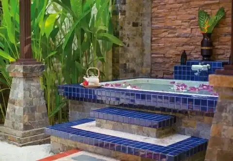 Privates Outdoor-Bad mit Whirlpool und tropischer Vegetation in einer Villa.