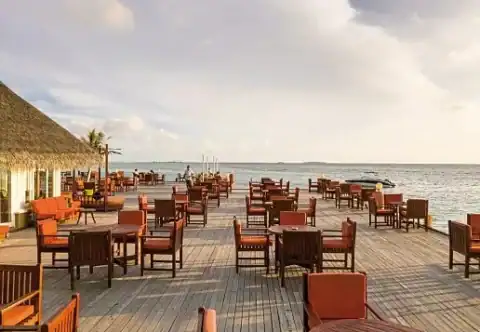 Holzterrasse mit Tischen direkt über dem Meer im Resortrestaurant.